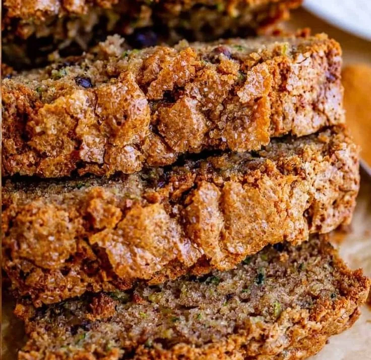 Slice of moist homemade zucchini bread on a wooden cutting board