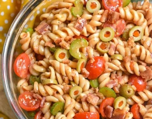 Bowl of Bloody Mary Pasta Salad with vibrant ingredients and garnishes