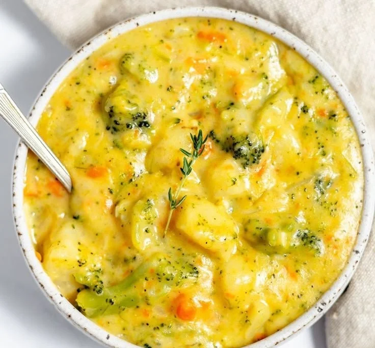 Bowl of creamy broccoli potato cheese soup topped with herbs