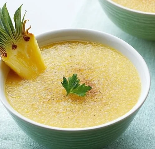 Chilled pineapple soup served in a bowl with fresh pineapple slices