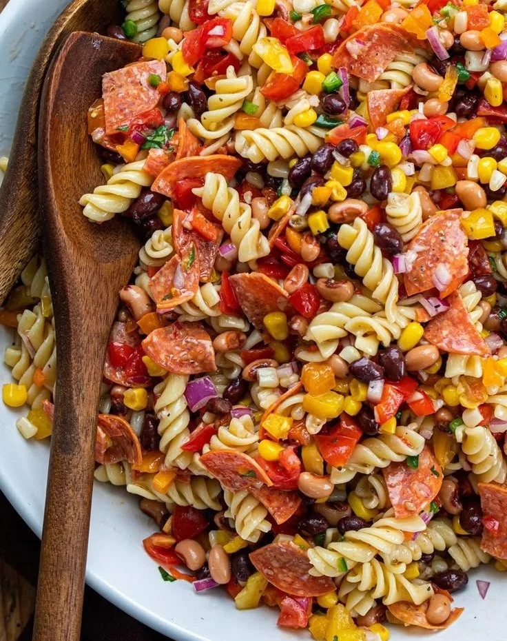 Bowl of vibrant Cowboy Caviar Pasta Salad topped with colorful vegetables and dressing.