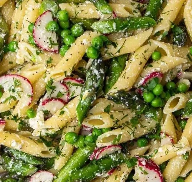 Creamy asparagus pasta salad with fresh vegetables and herbs