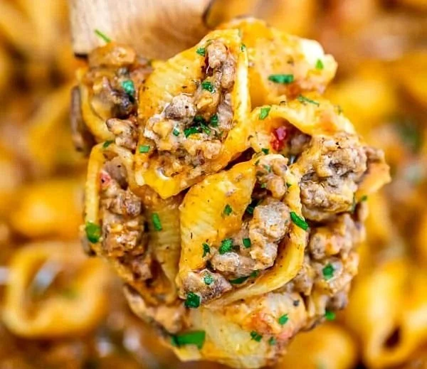 Creamy beef and shells dish served in a bowl with fresh herbs