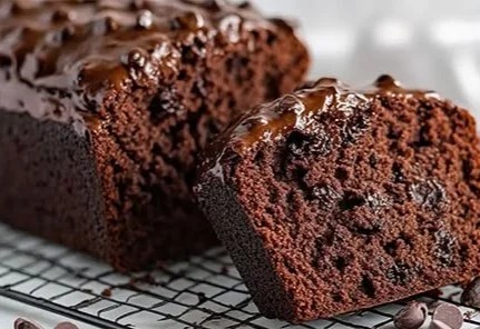 Slice of double chocolate zucchini bread topped with chocolate chips and fresh zucchini
