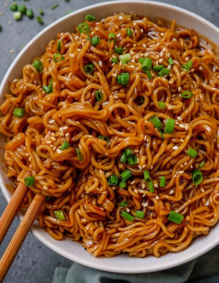 Bowl of easy saucy ramen noodles topped with green onions and sesame seeds