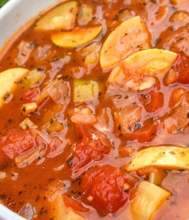Bowl of Italian summer soup garnished with fresh herbs.