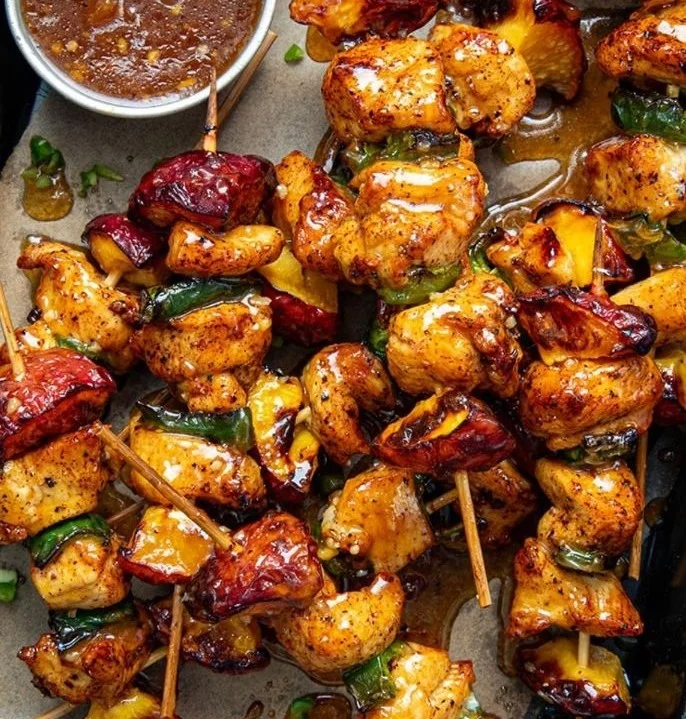 Jalapeno Peach Chicken Skewers on a wooden platter garnished with herbs