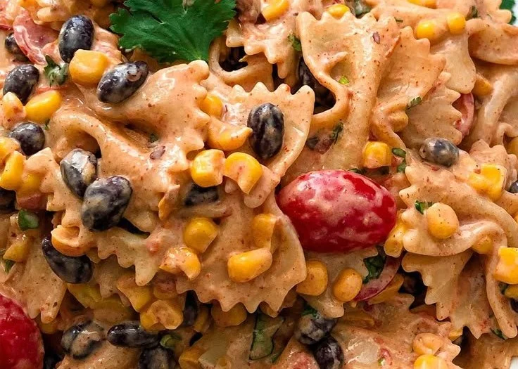 A colorful bowl of Mexican Pasta Salad with fresh vegetables and herbs.