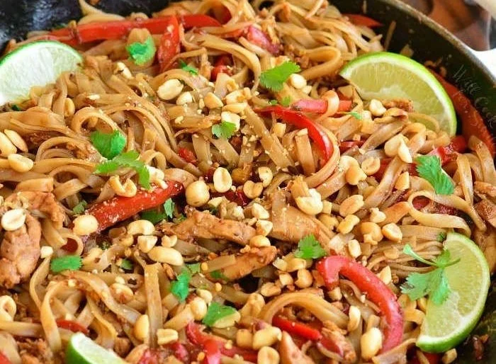 Delicious Pad Thai served with chicken, peanuts, and fresh herbs on a plate