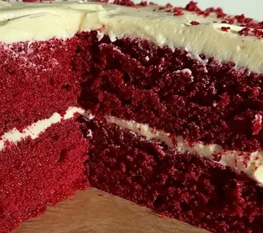 Delicious slice of Red Velvet Cake with cream cheese frosting on a plate.