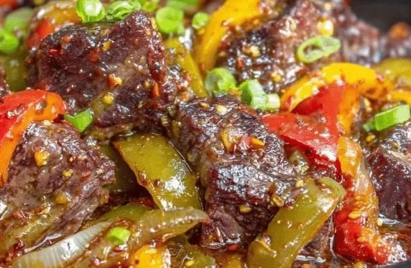 A delicious plate of slow cooker pepper steak garnished with fresh herbs.