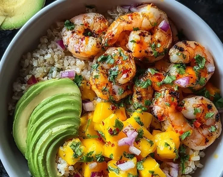 Delicious Shrimp Avocado Bowls with Mango on a plate garnished with herbs