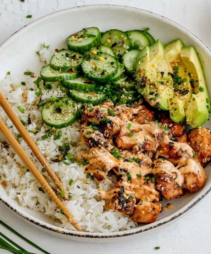 Spicy salmon bowl served with coconut rice and fresh vegetables.