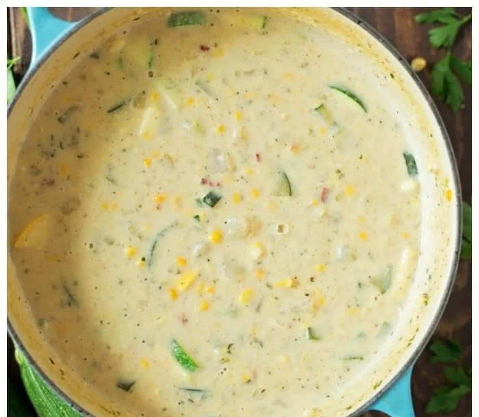Bowl of fresh summer Corn and Zucchini Chowder topped with herbs