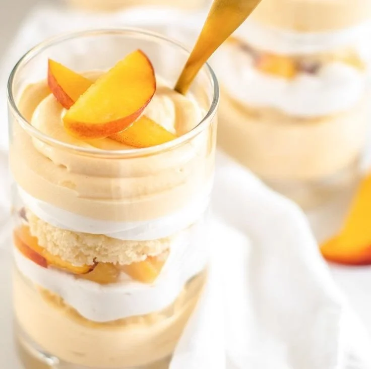 Summer Peach Mousse Trifle with layers of peach and cream served in a glass.