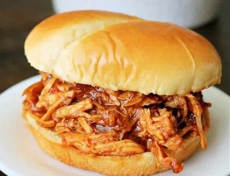 Delicious pulled BBQ chicken made in a Crockpot, served on a plate.