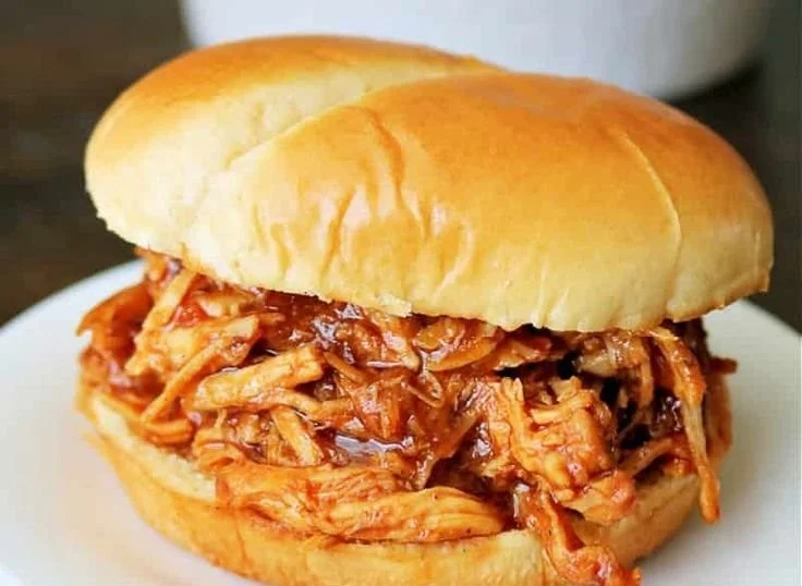 Crockpot BBQ chicken served with side dishes on a wooden table