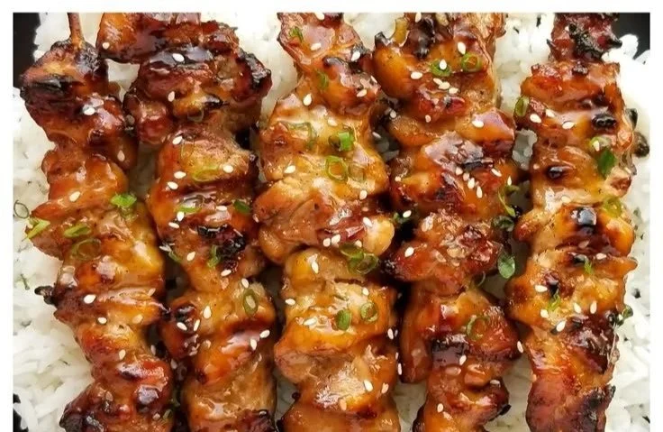 Delicious teriyaki chicken skewers garnished with green onions and sesame seeds.