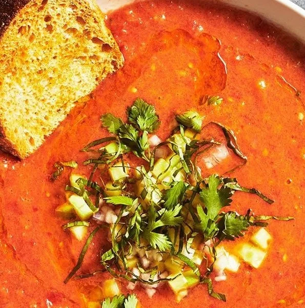 Bowl of refreshing watermelon gazpacho garnished with herbs