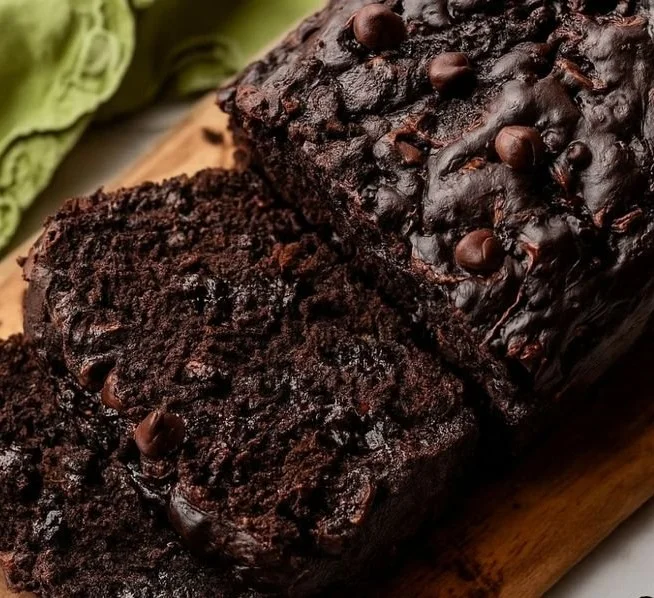 A slice of moist, homemade zucchini bread on a wooden cutting board