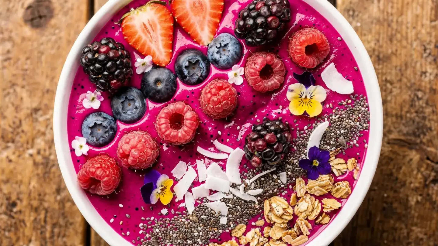 Berry Pitaya smoothie bowl topped with fresh fruits and seeds