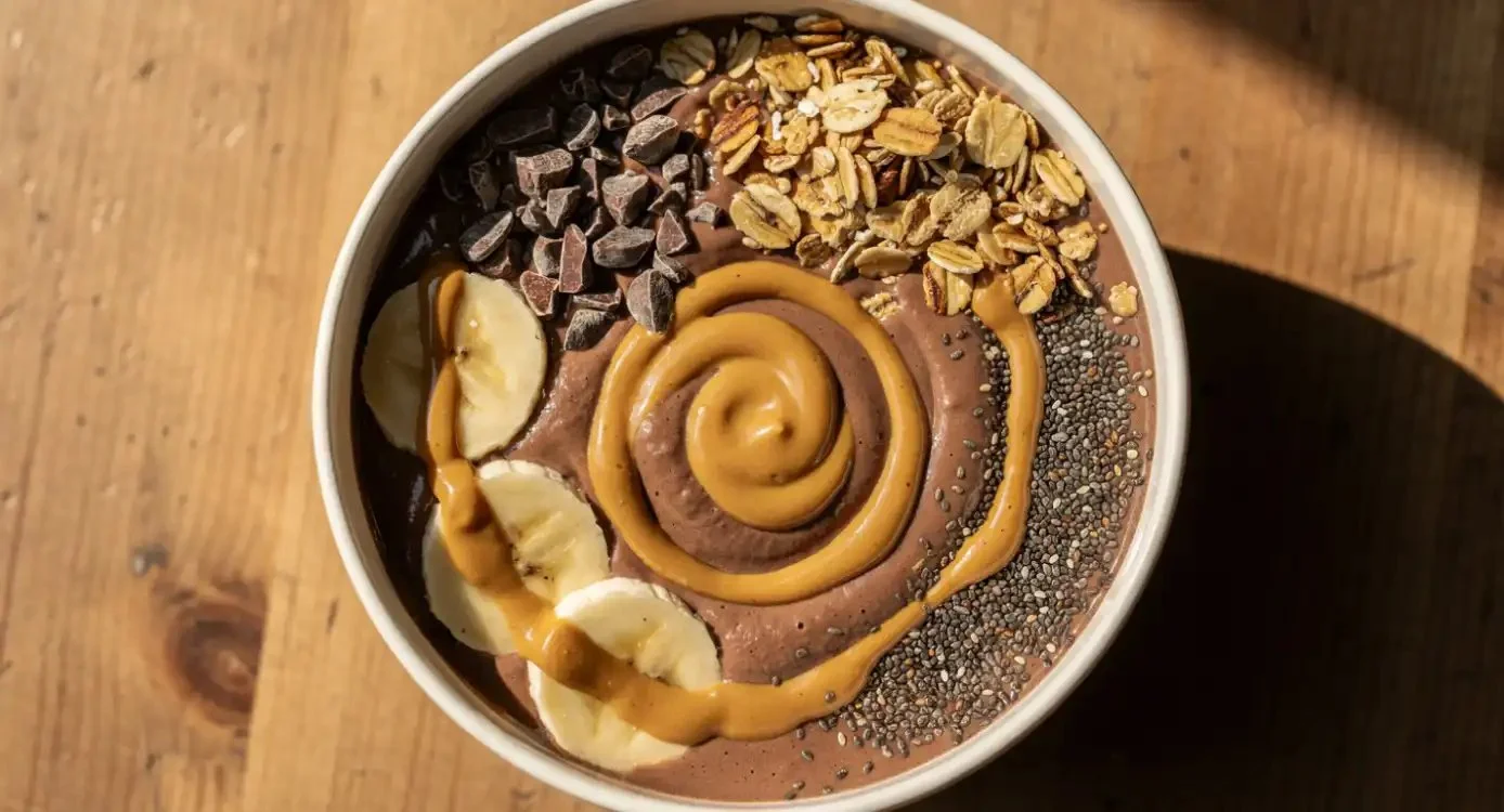 Chocolate peanut butter smoothie bowl topped with fresh fruits and nuts.