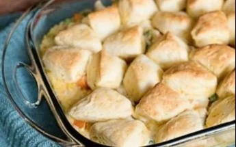 Creamy chicken pot pie with a flaky biscuit crust on a wooden table