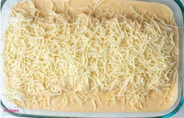 Creamy white chicken enchiladas topped with cheese and herbs on a plate.