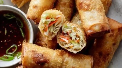 Golden crispy spring rolls filled with vegetables and served with dipping sauce