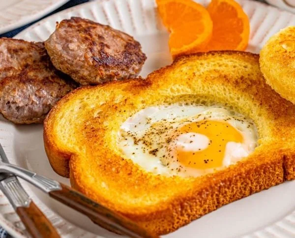 Delicious egg in a hole served with toast and fresh herbs.