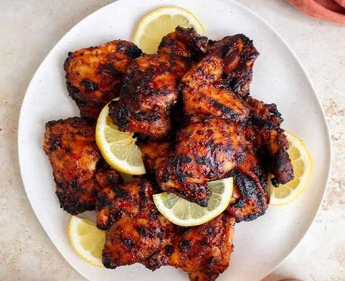 Grilled BBQ chicken thighs on a barbecue grill, showcasing delicious caramelization.