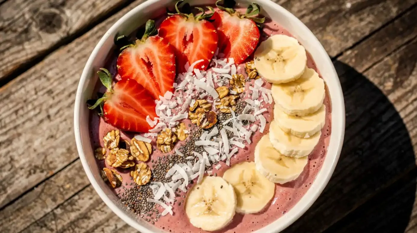 Strawberry banana smoothie bowl topped with fresh fruits and granola.