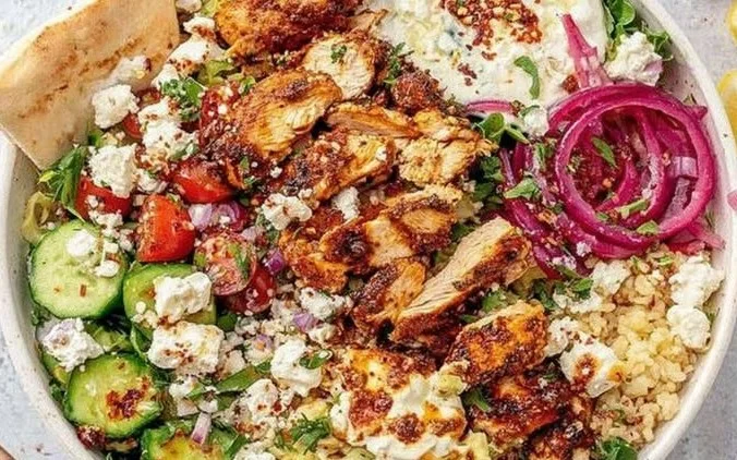 Cava Honey Harissa Chicken Bowl topped with fresh ingredients and sauces