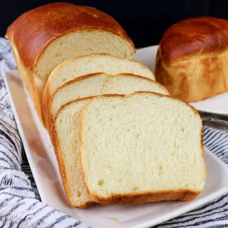 Freshly baked homemade Amish White Bread loaf on a wooden cutting board.