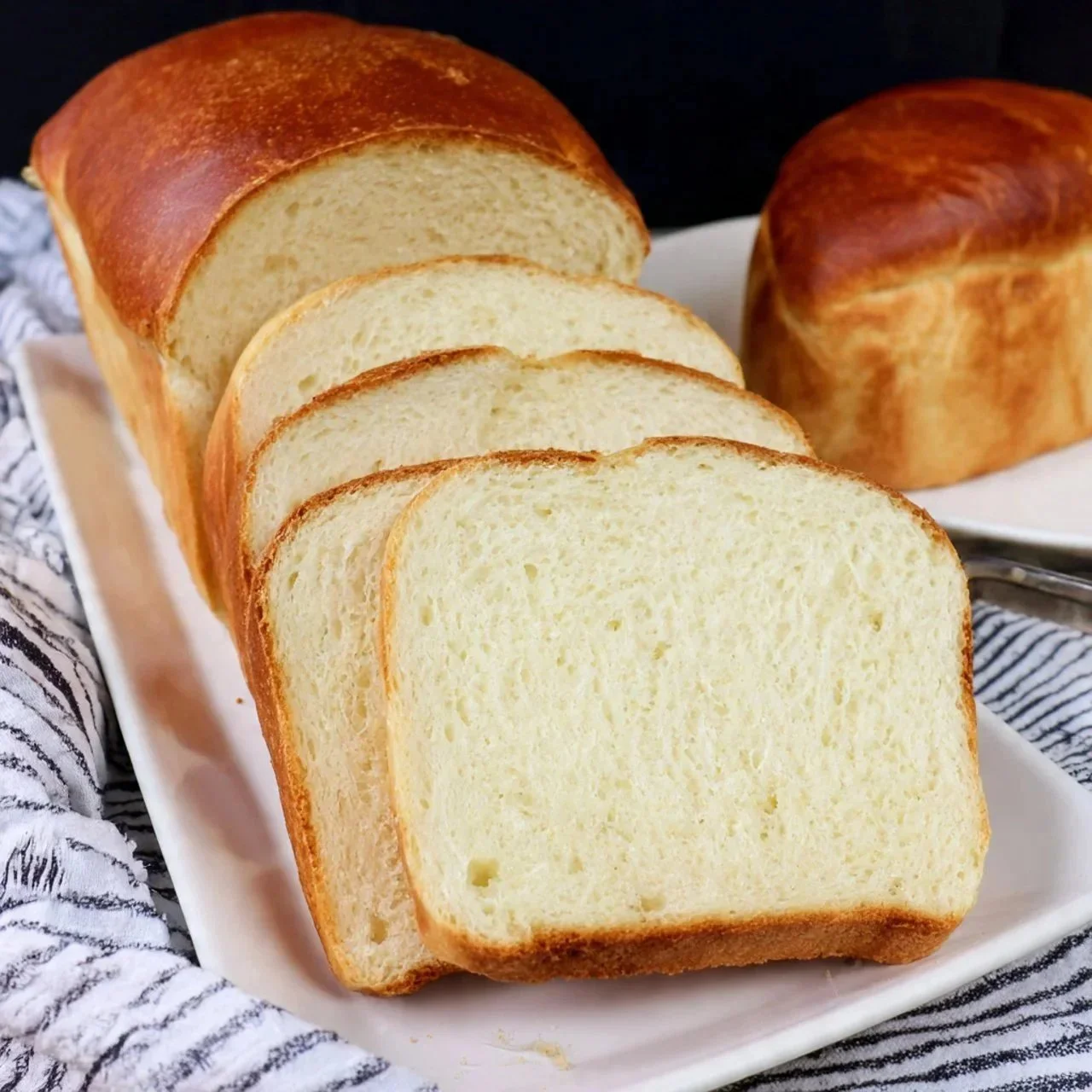 Freshly baked homemade Amish White Bread loaf on a wooden cutting board.